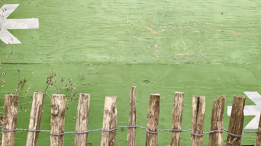 brown wooden stick fence near green wall