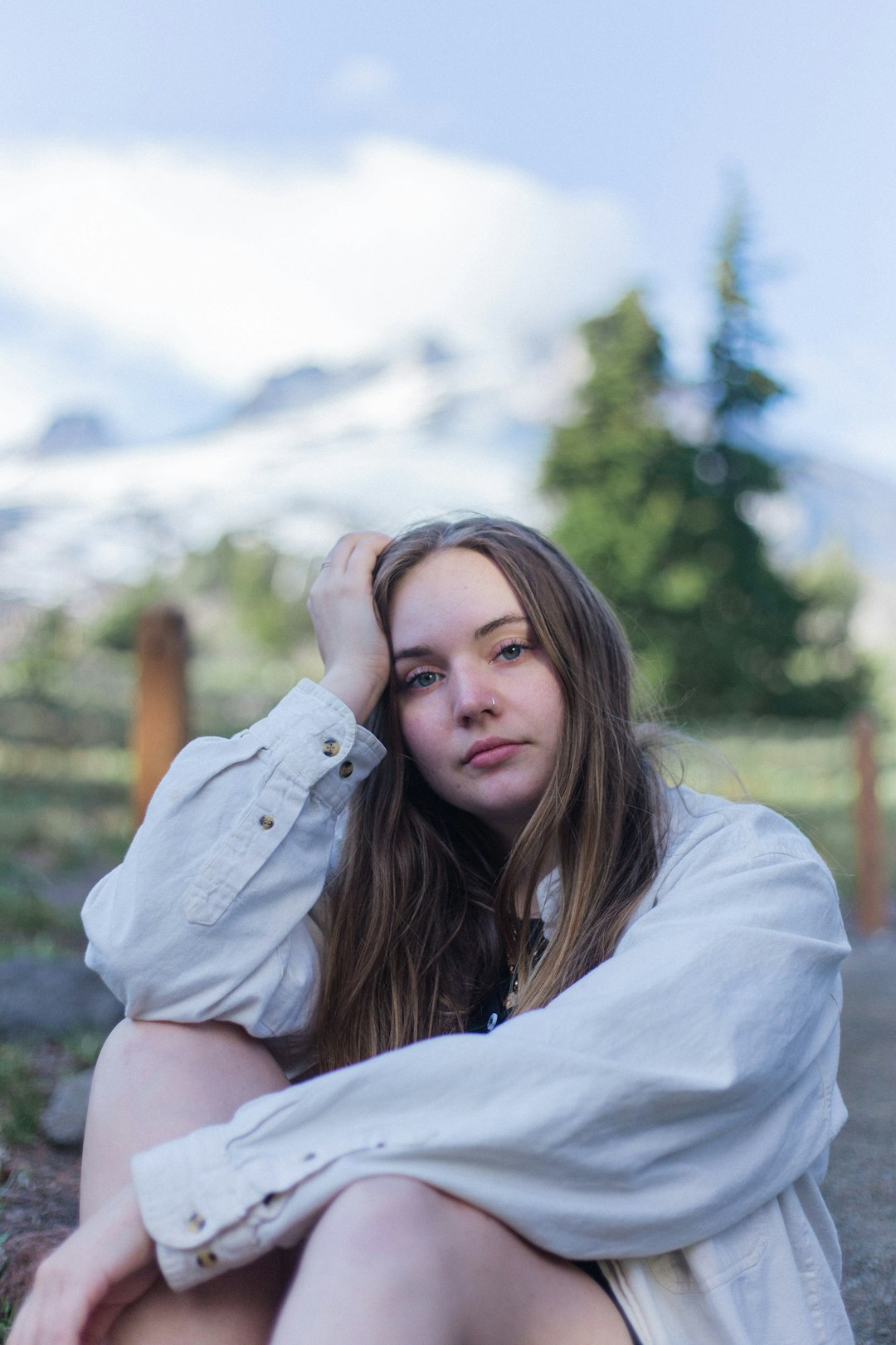 woman wearing white denim jacket sitting while touching her head