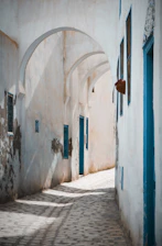 A serene Cycladic alley bathed in soft morning light, framed by whitewashed walls and delicate shadows.