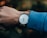 Close-up of a minimalist wristwatch on a wrist with a casual outfit background.