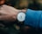 Close-up of a minimalist wristwatch on a wrist with a casual outfit background.