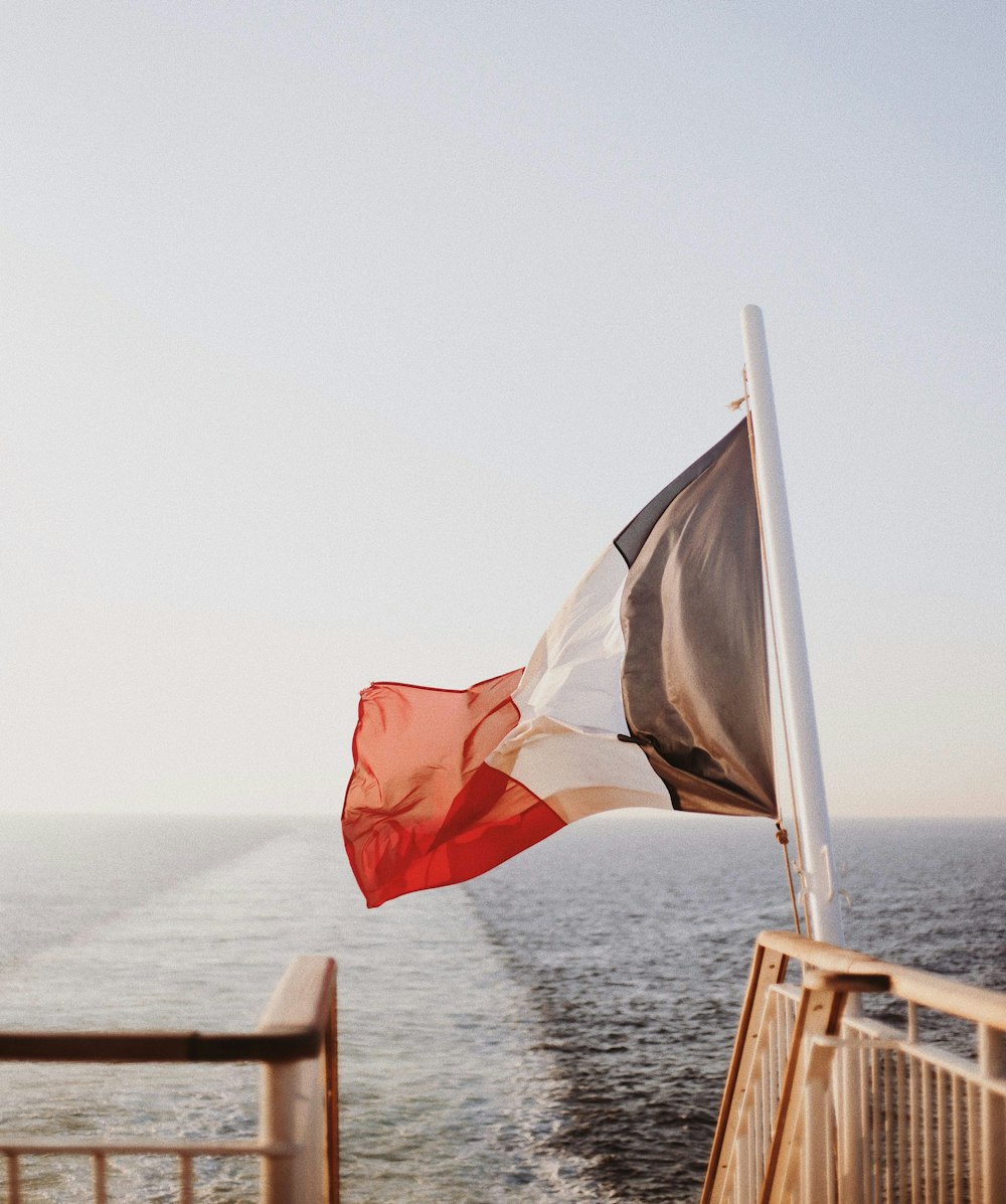 Drapeau blanc, rouge, blanc et gris flottant près de la mer pendant la journée