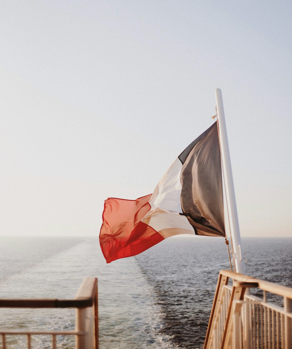 昼間、海の近くでなびく白、赤、白、灰色の旗