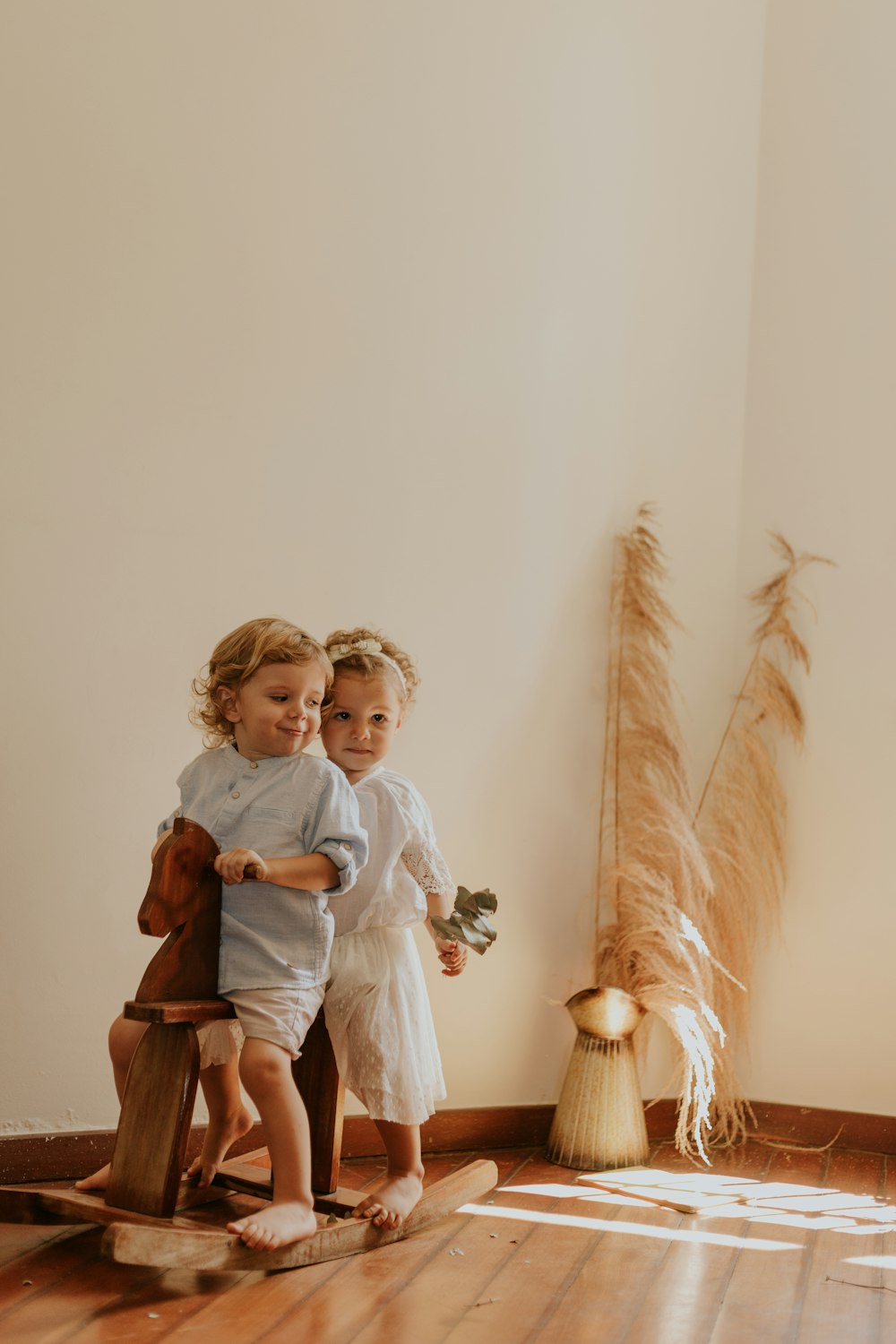 two toddlers riding rocking horse near wall