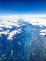 An aerial view of Zanskar River, surrounded by snow-capped mountains and clear blue skies.