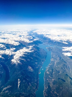 An aerial view of Zanskar River, surrounded by snow-capped mountains and clear blue skies.