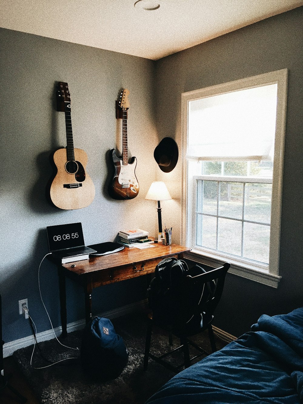 brown acoustic guitar near brown and black electric guitar hanging on wall