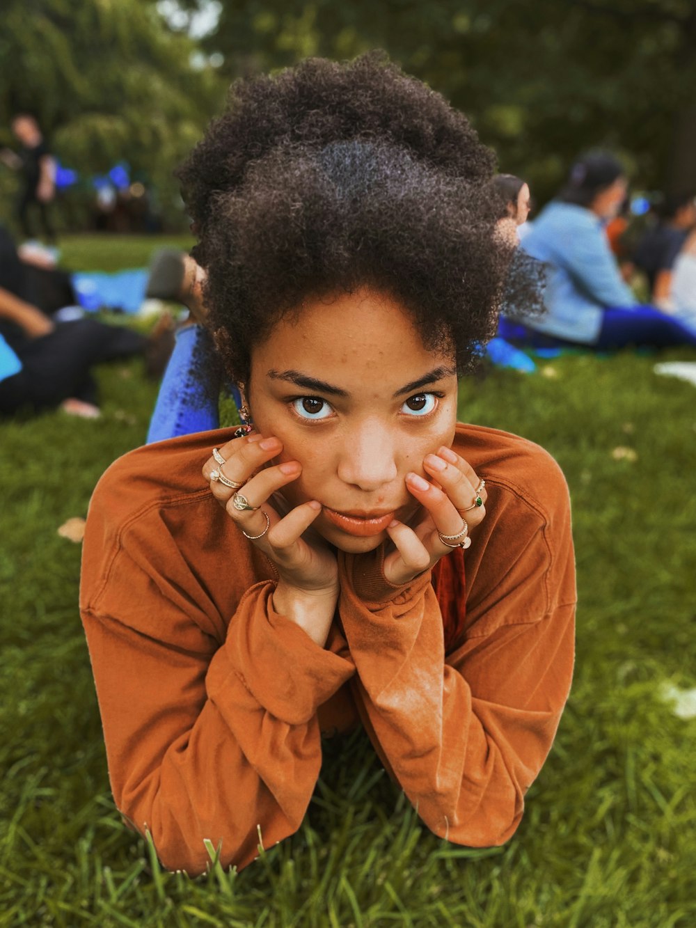 woman lying on grass with hands or her chin