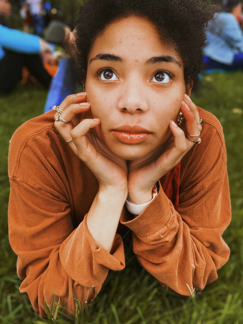 woman resting head on both hands prone lying on green grass