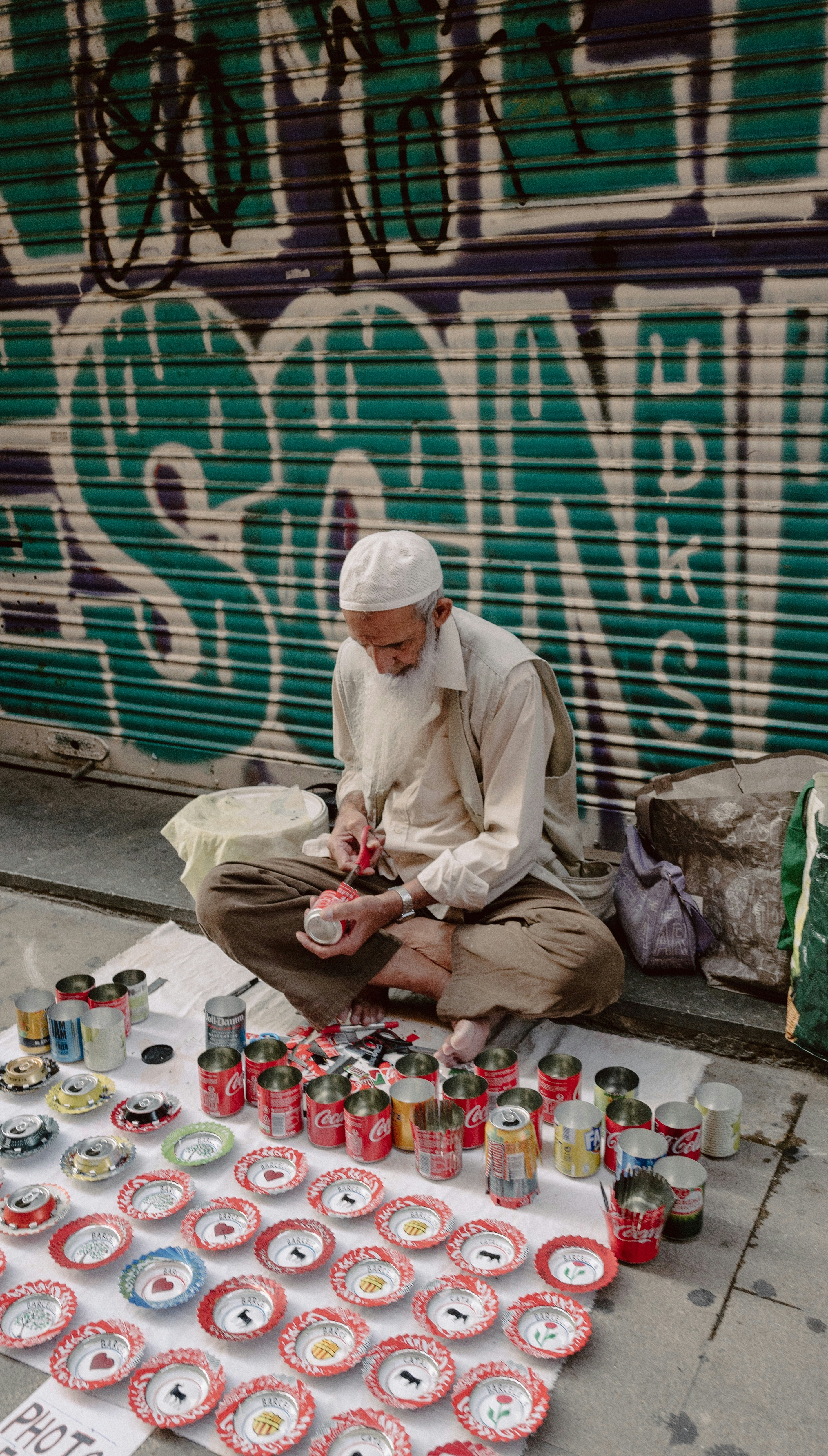 sitting man on sidewalk doing can decoration
