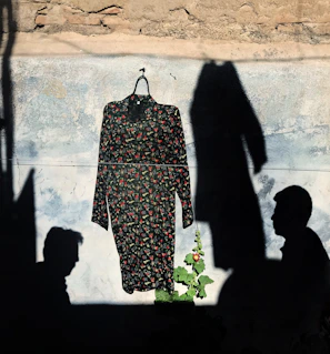 A vintage floral dress displayed on a wooden hanger against a soft beige background