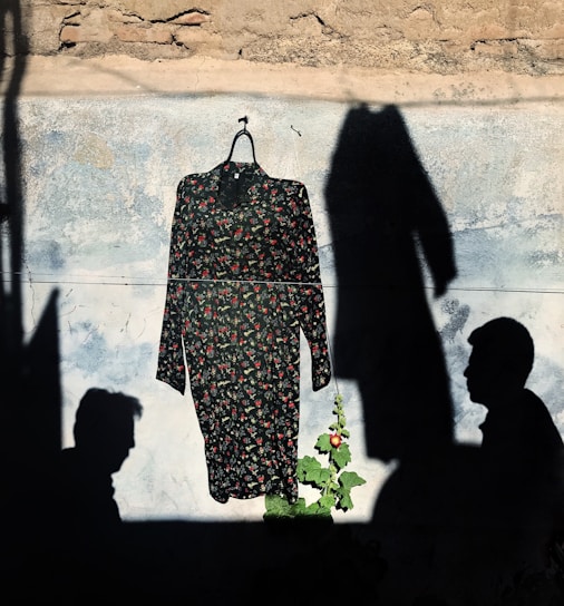 A vibrant photo of a flowing floral dress hanging on a rustic wooden rack in soft natural light.