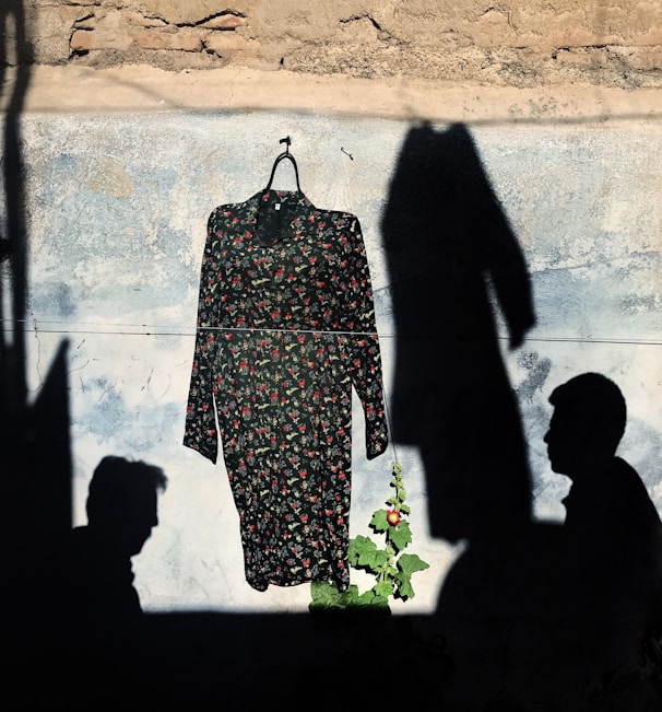 Close-up of a bright floral summer dress hanging near a sunlit window