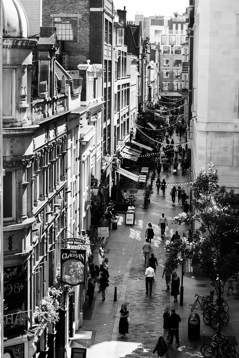 grayscale photography of people walking between buildings