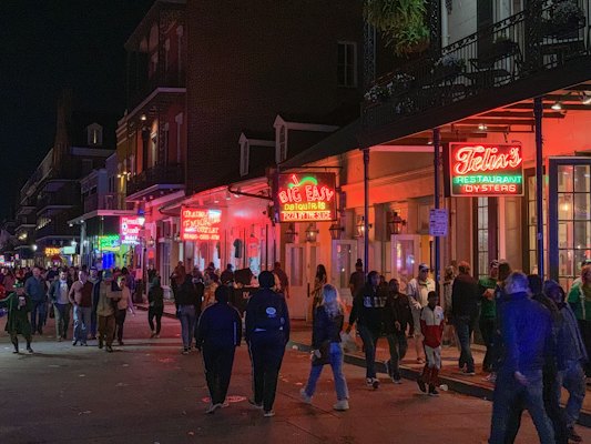 Bourbon Street at night, the balconies and the neon above the crowd — New Orleans, United States
