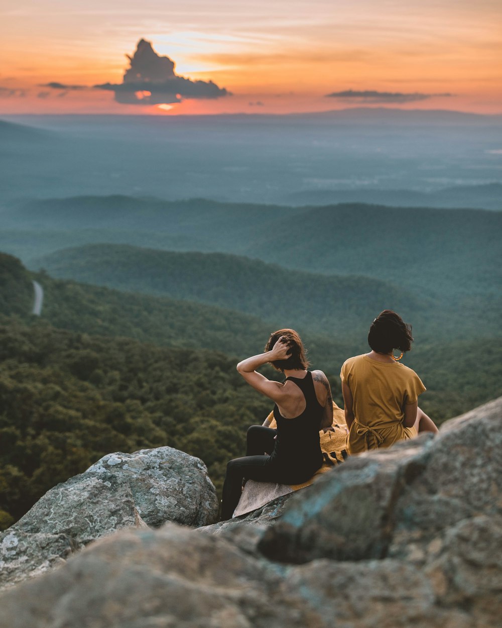 two women sitting on rock formation