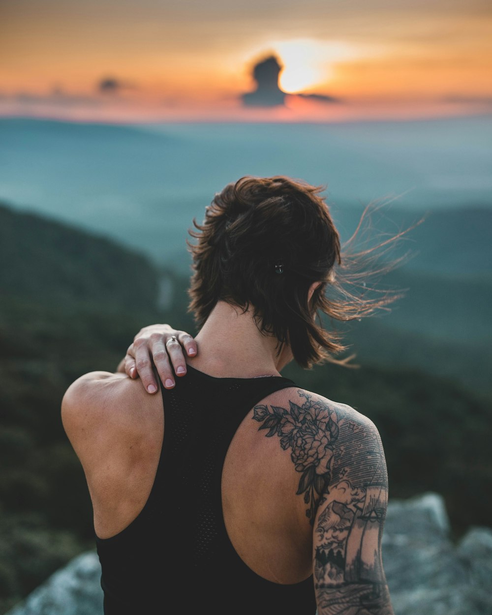 person wearing black tank top standing while touching back