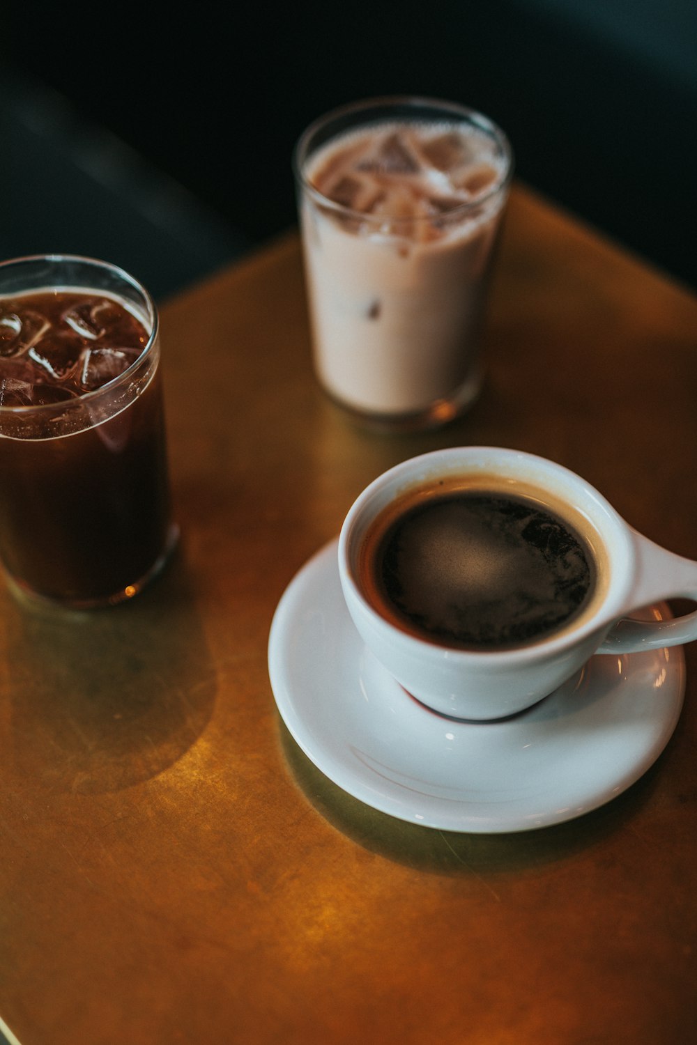 three cups of drinks on brown table