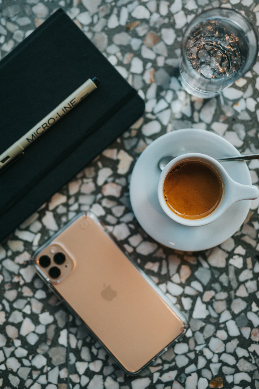 gold iPhone 11 beside cup on table