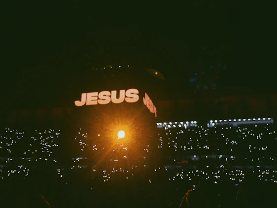 A joyful crowd worshipping together under soft blue lights at an outdoor Christian festival in Côte d'Ivoire.