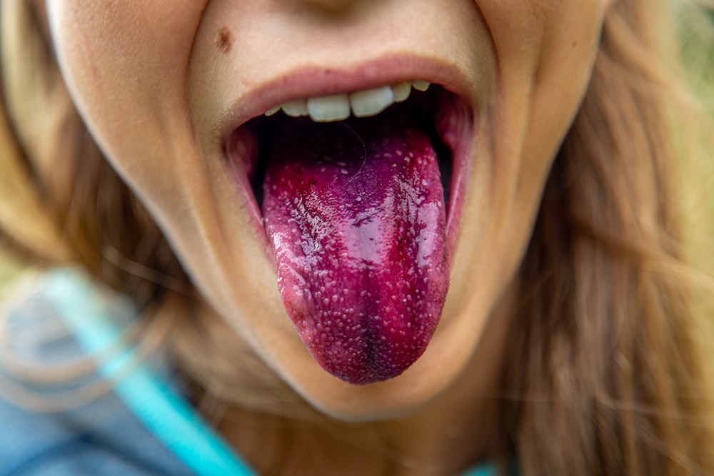Mujer mostrando lengua con color púrpura durante el día