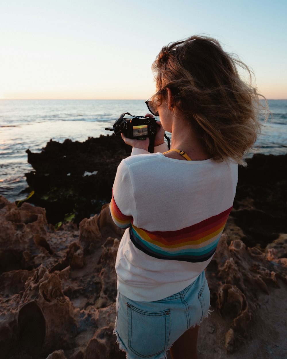 woman taking photo of seashore during daytime