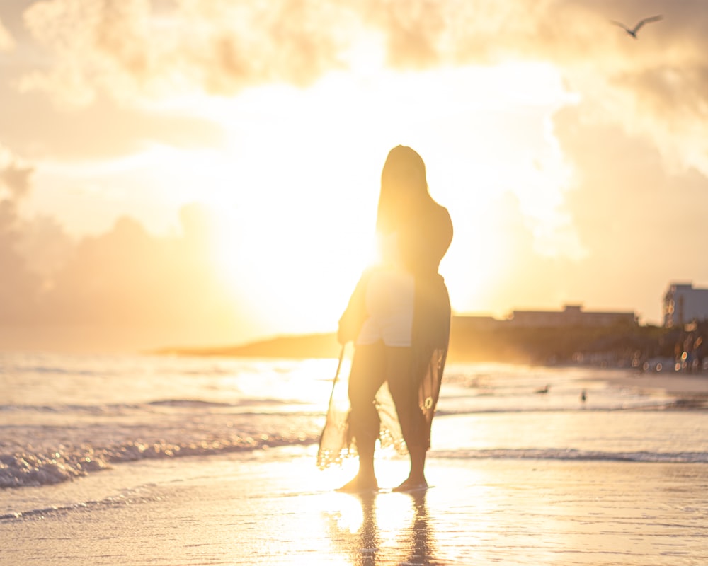 silhouette of woman walking on seashore