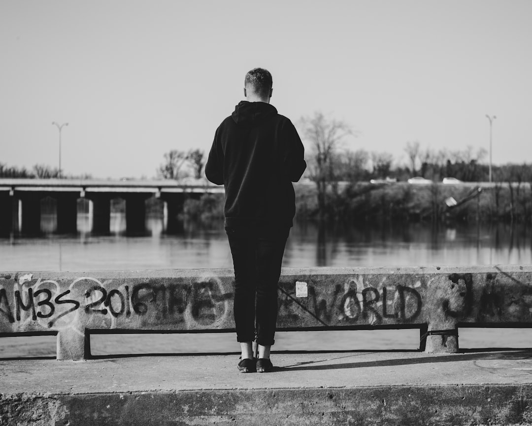 grayscale photography of woman standing on bridge