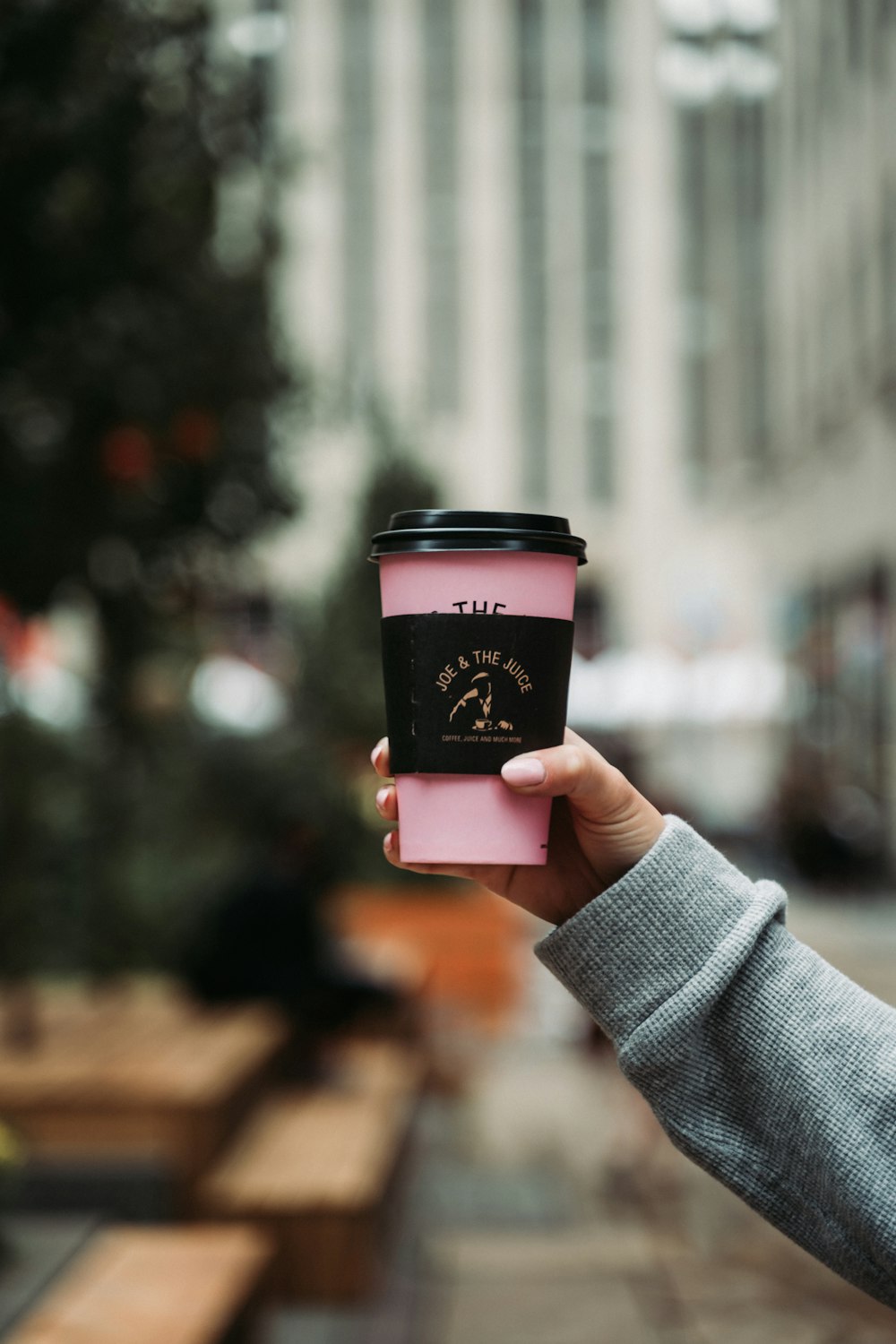 person holding pink and white coffee cup