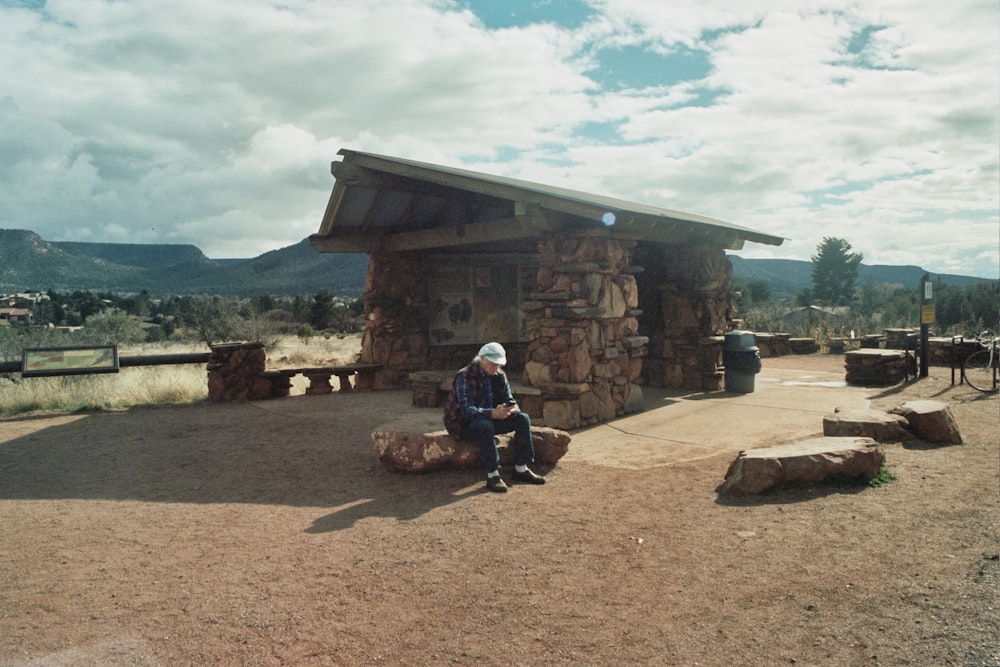 man sitting on a slab outside a chalet house