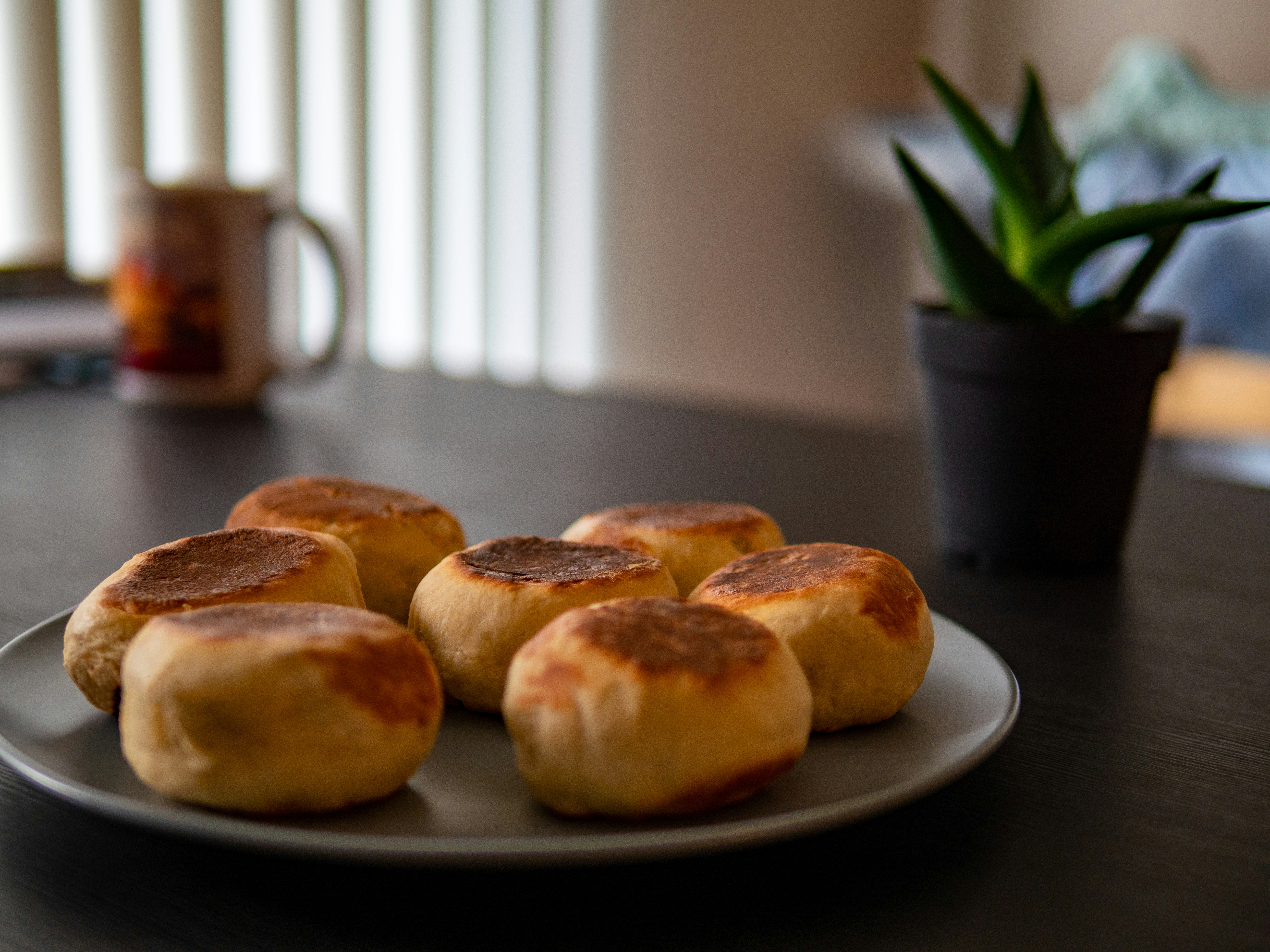 Four golden-brown crumpets on a dark plate, ready to serve