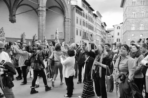 A group of tourists smiling and taking photos in front of a famous historic landmark.
