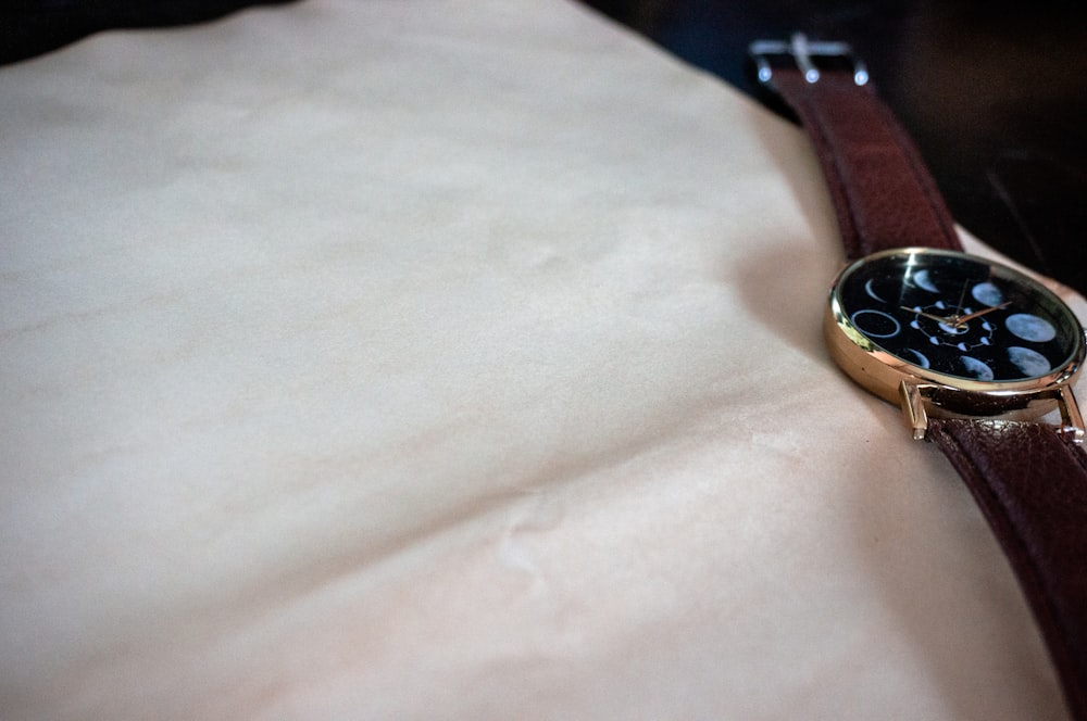 round gold-colored watch with brown leather strap