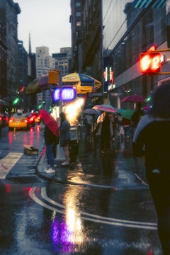 A misty Chennai street scene during monsoon, with colorful umbrellas and wet pavements reflecting city lights.