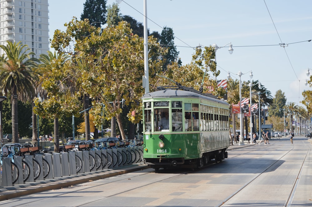 green tram on road viewing high-rise buildings during daytime