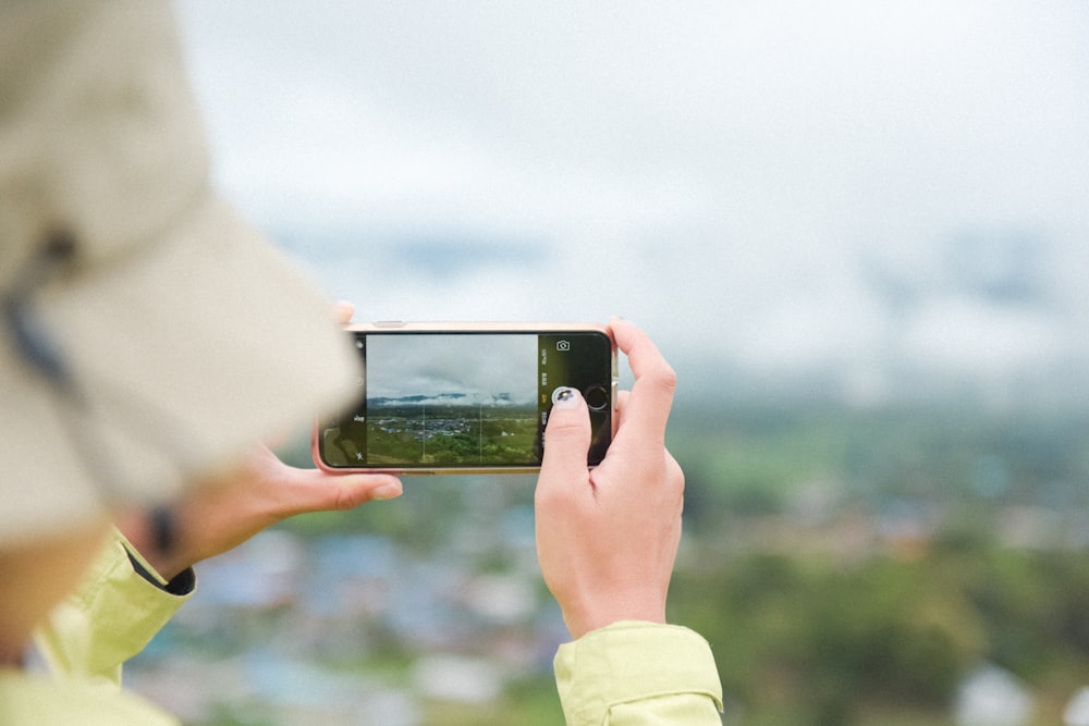 person taking photo of green field