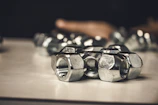 Stack of stainless steel nuts and bolts reflecting light in a workshop