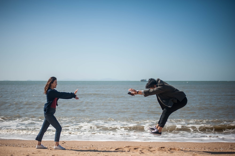 two people playing on seashore during daytime