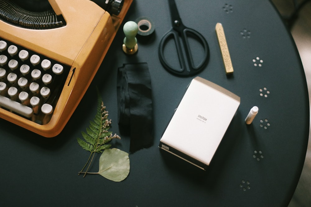 brown typewriter beside scissors and box on table