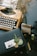 An eclectic desk arrangement featuring an old-fashioned typewriter with visible keys, a vase of dried flowers, a boxed gift adorned with a decorative wax seal and foliage, and an instant photo placed on top. Additional items include a rubber stamp, a tape dispenser, and other small stationary items scattered around.