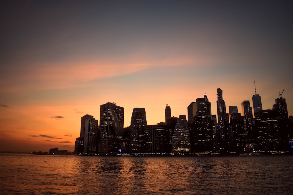 silhouette of high-rise building beside sea during golden hour