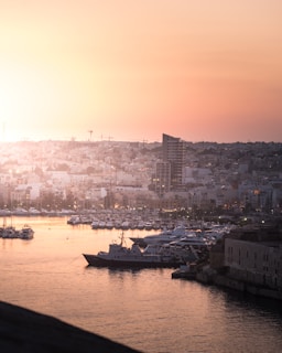 The iconic Kobe Harborland skyline at sunset, with boats gently bobbing in the harbor waters.
