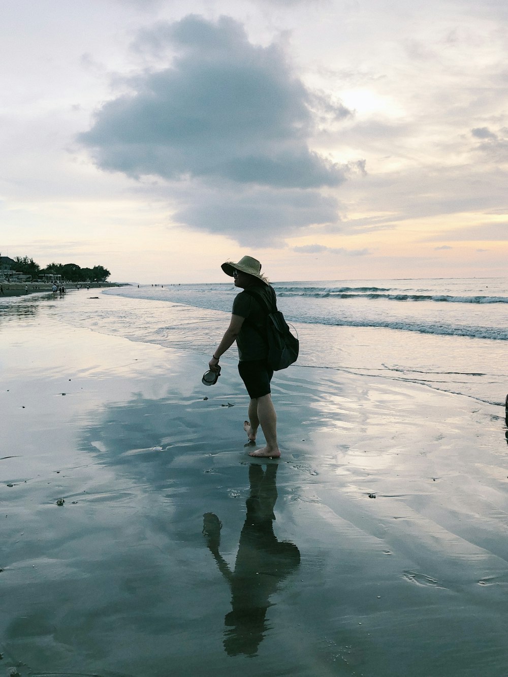 Frau im schwarzen Kleid, die tagsüber am Meer spazieren geht