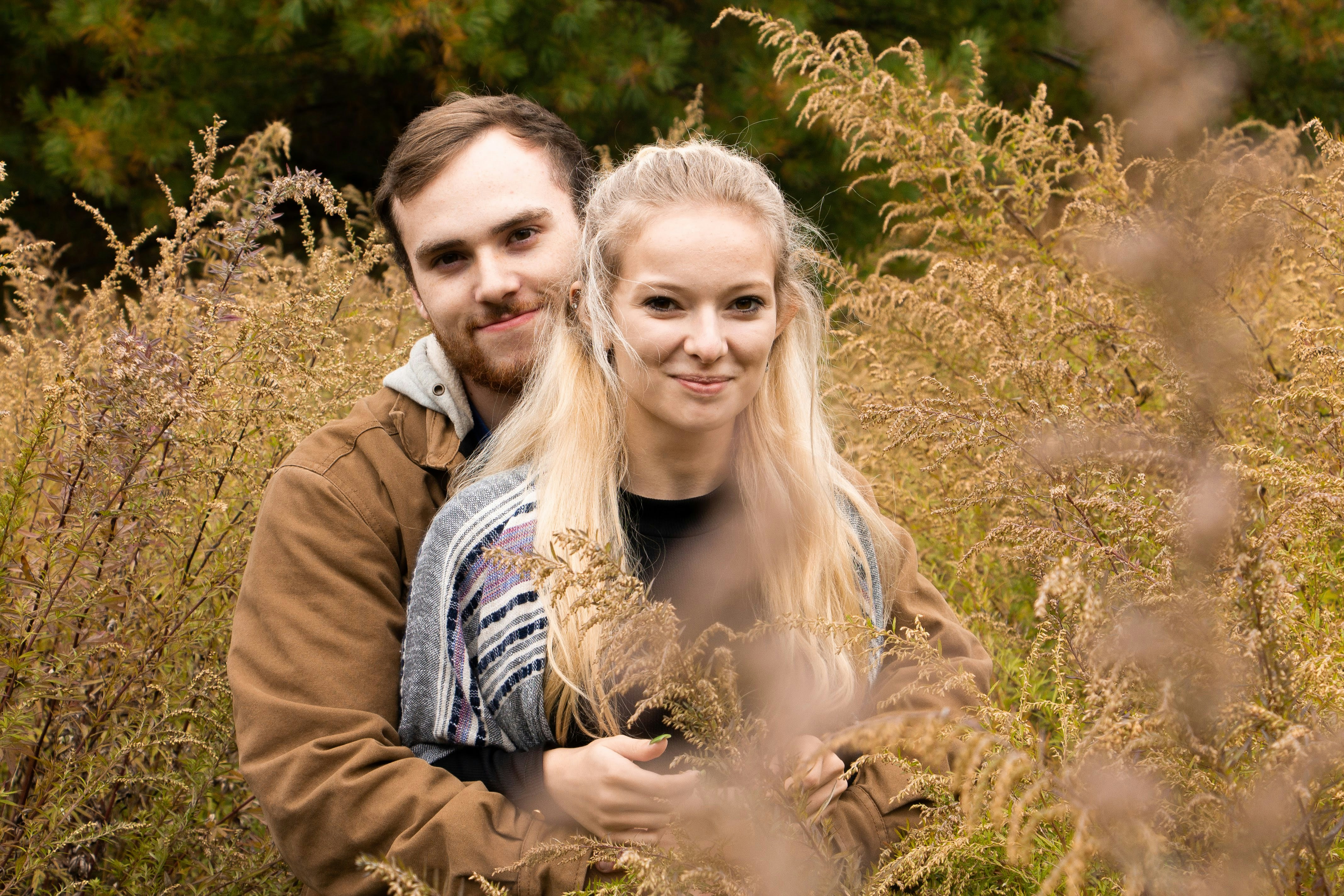 Shallow focus photo of man hugging woman