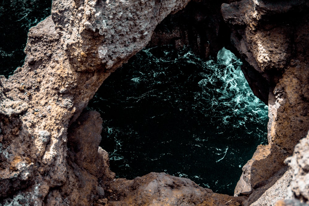 a view of the ocean through a hole in the rocks