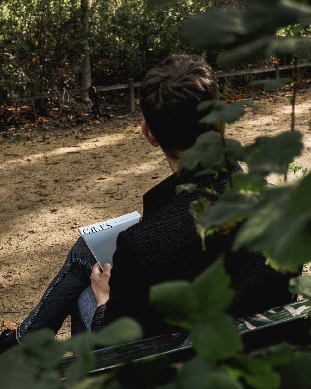 man wearing black long-sleeved shirt sitting on bench