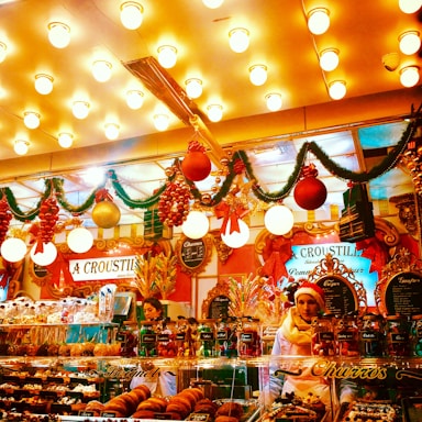 A cozy shop front of Vinayak Sweets glowing warmly in festive maroon and saffron lights.