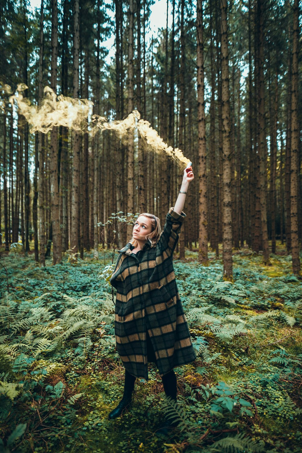 woman in green and brown coat holding flare