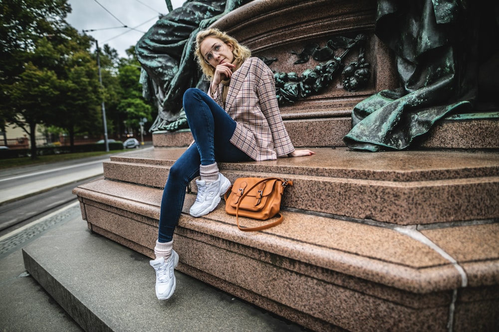 woman sitting on concrete panel beside statue