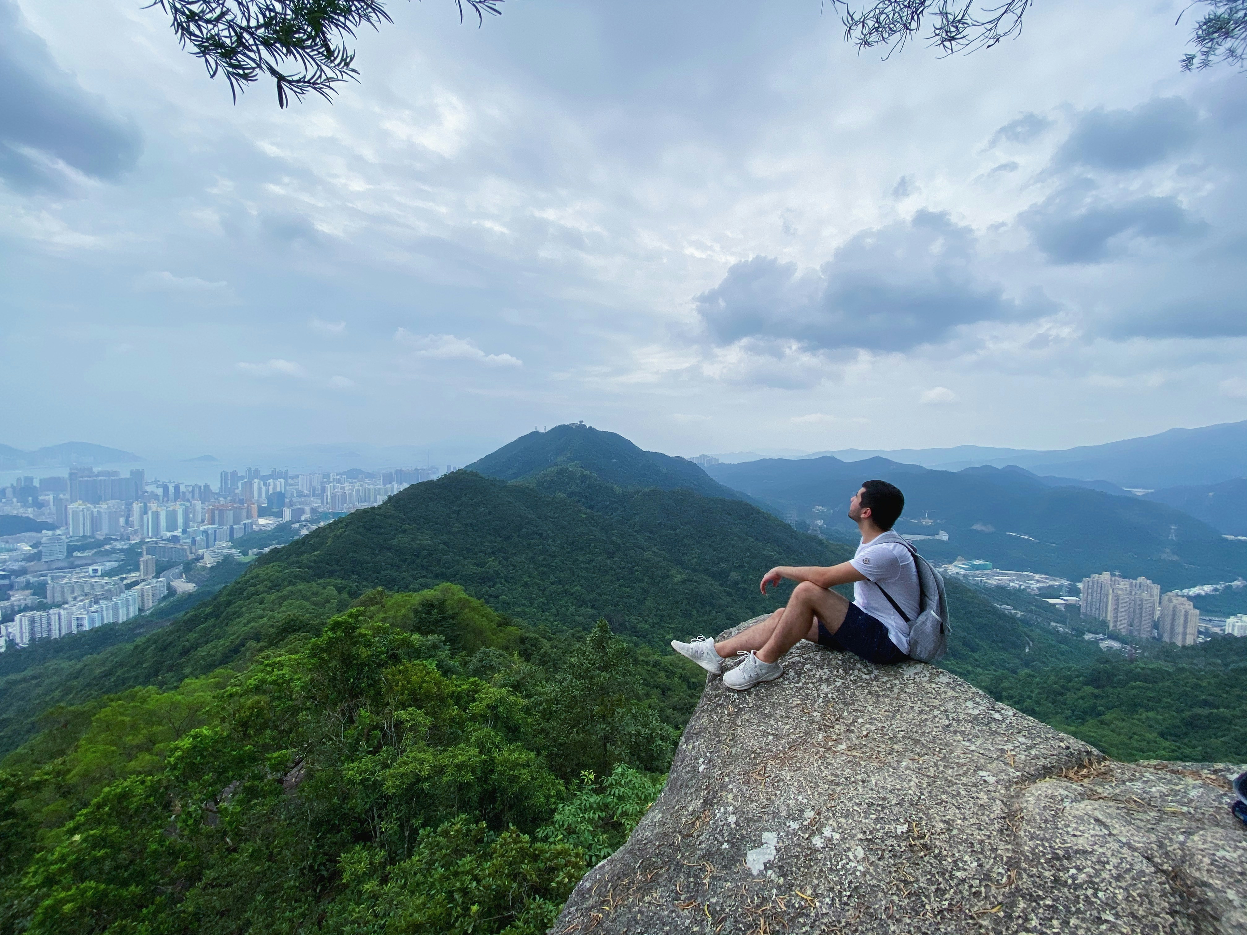 homme portant une chemise blanche assis sur des collines verdoyantes